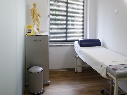 Ein Untersuchungszimmer mit einer Liege und einem Schrank.