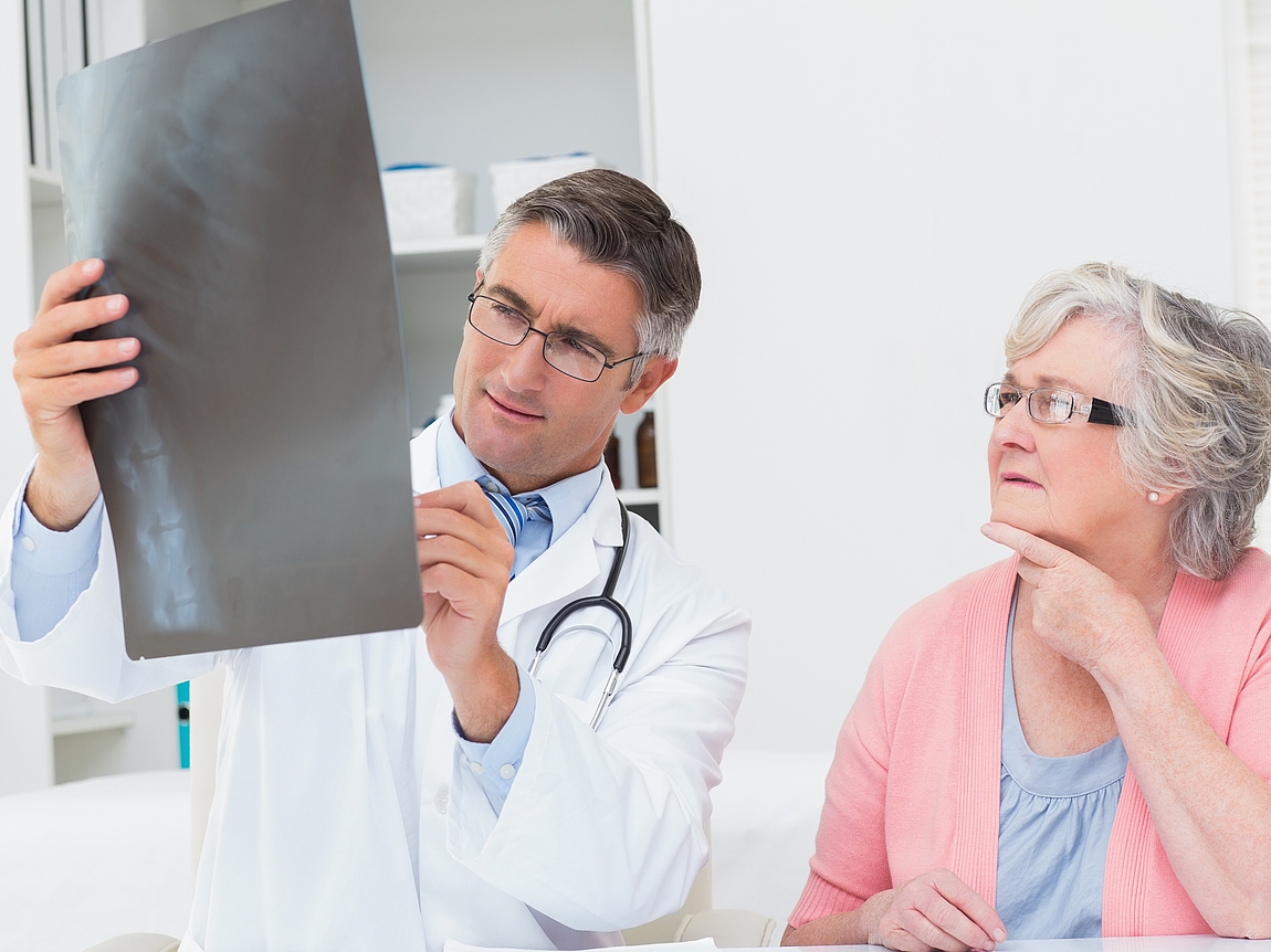 Überprüfung der Knochendichte Arzt und Patientin betrachten eine Röntgenaufnahme