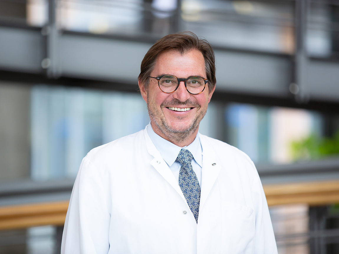 Ein Arzt lächelt in die Kamera.