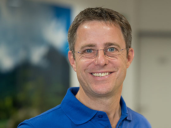 Ein Mitarbeiter des Orthozentrum Miesbach lächelt in die Kamera.